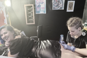 Lucy tattooing her friend on the back of the thigh at the Wildstyle Tattoo Convention 2021